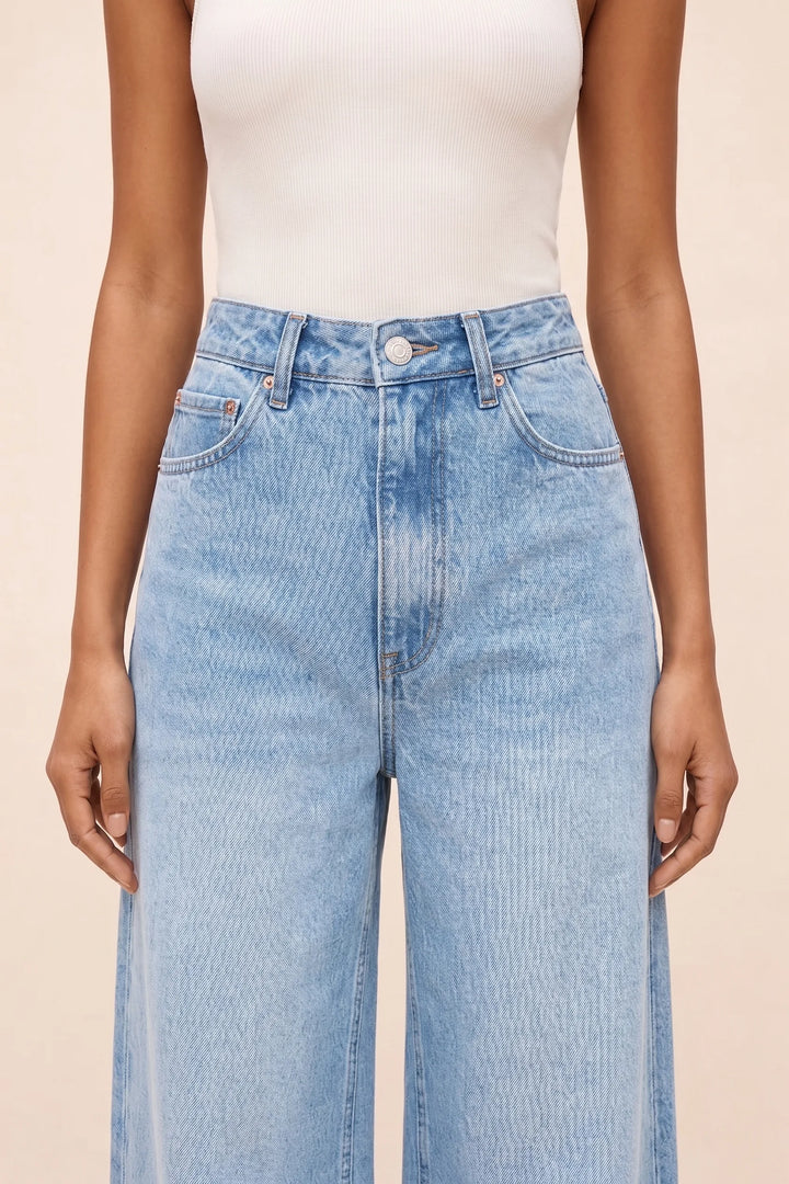 Close-up detail of wide-leg blue denim fabric and stitching
