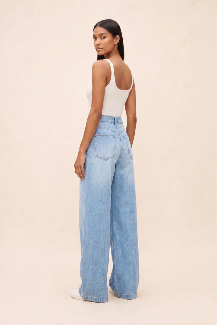 Woman wearing wide-leg blue jeans in a three-quarter turn pose