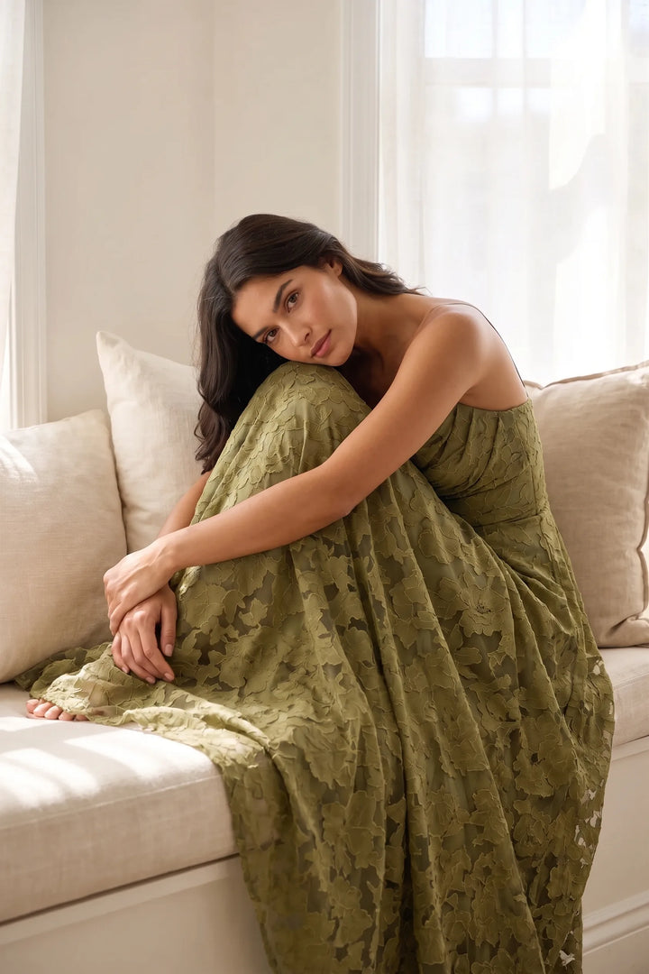 Model wearing an olive green lace open-back gown in an outdoor lifestyle setting