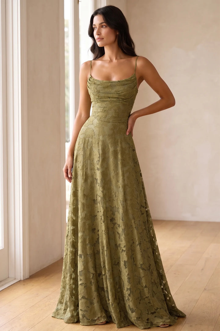 Model wearing an olive green lace open-back gown in a lifestyle setting