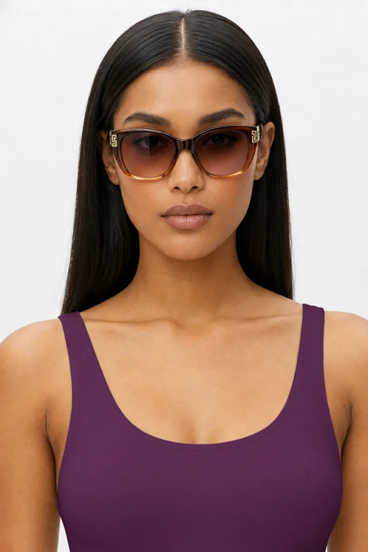 Woman wearing oversized square cat-eye sunglasses in deep purple, front-facing close-up