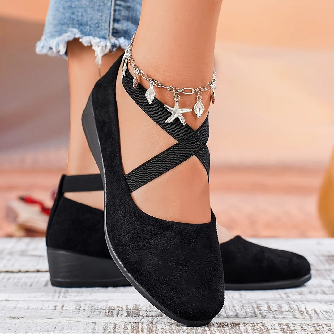 Black cross strap low wedge flat, close-up detail of cross strap