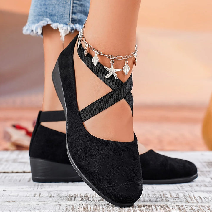 Black cross strap low wedge flat, close-up detail of cross strap
