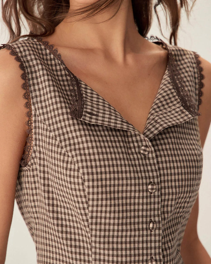 Woman in a three-quarter turn wearing a brown gingham top with lace trim
