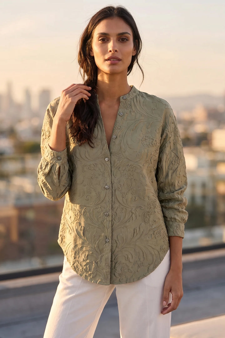 Model wearing green embossed floral blouse in a lifestyle setting