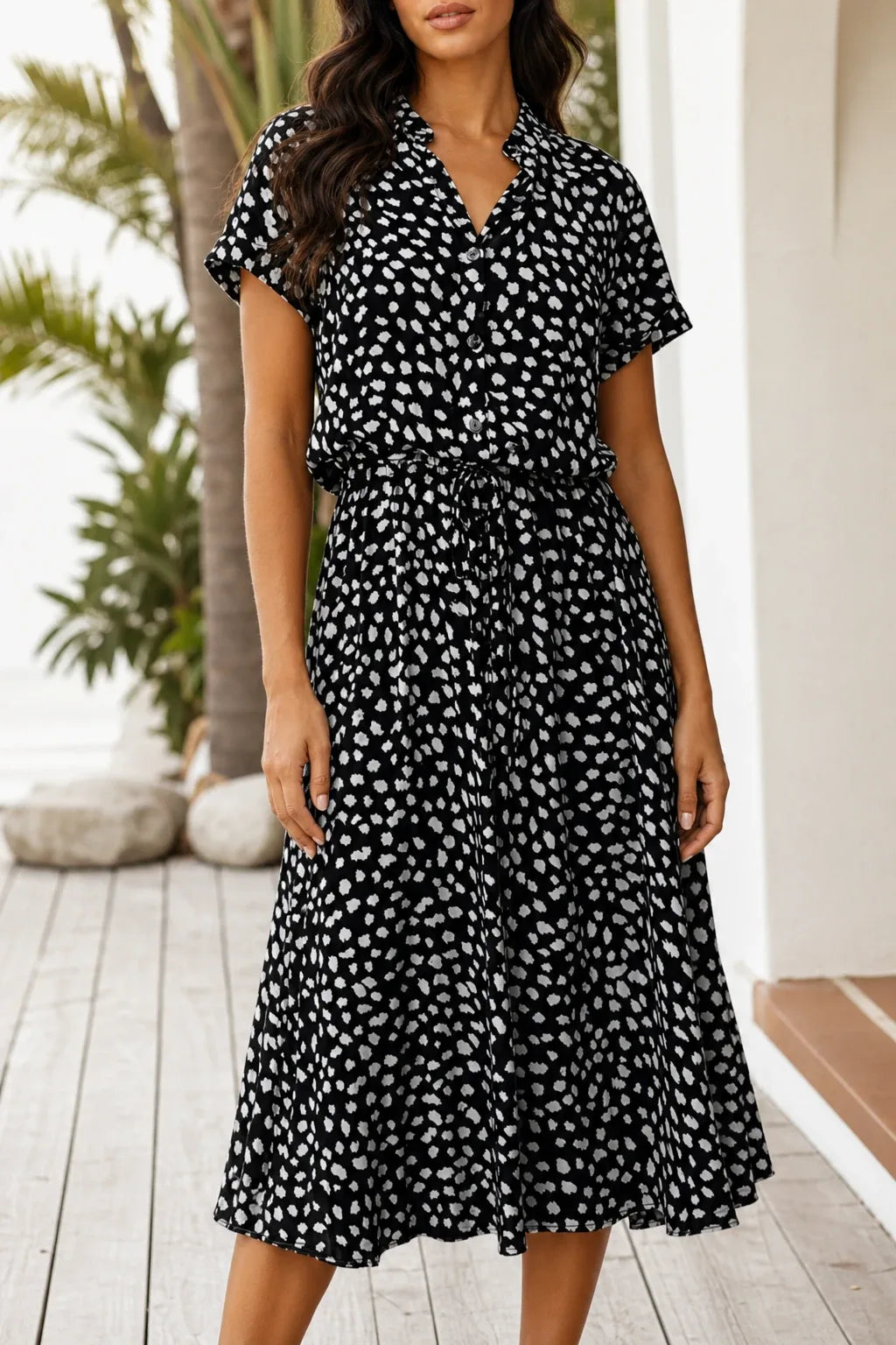Black spotted print midi dress on model in contrapposto stance