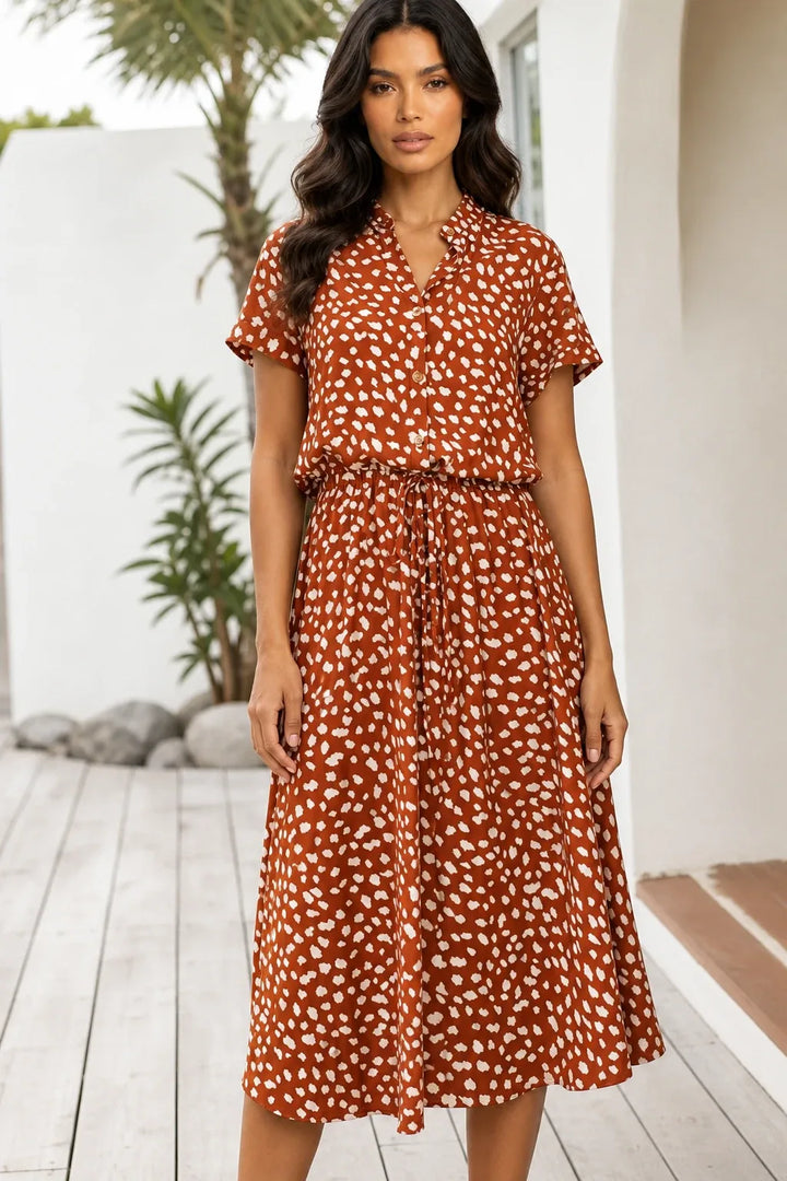 Orange spotted print midi dress on model in contrapposto stance