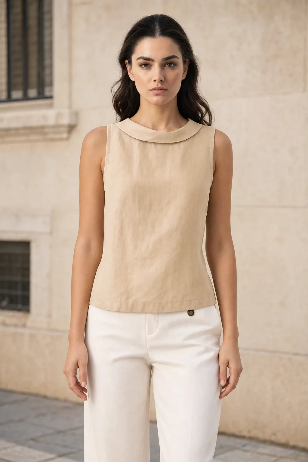 Beige sleeveless blouse with roll collar on model in contrapposto stance