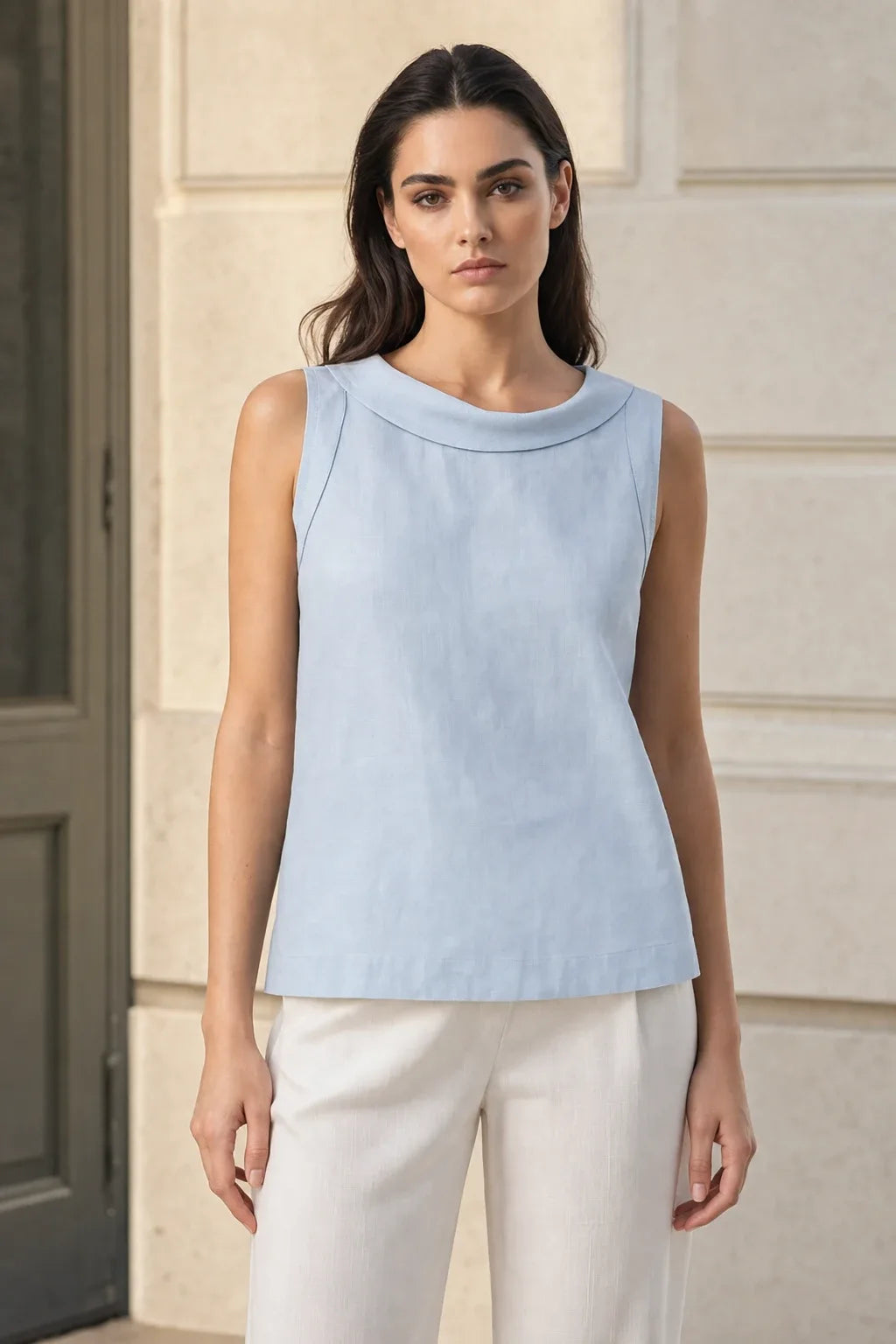 Blue sleeveless blouse with roll collar on model in contrapposto stance