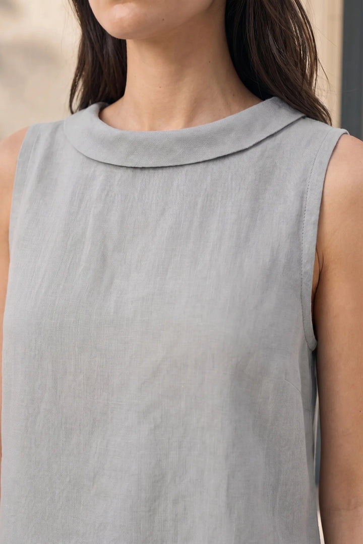 Close-up detail of grey sleeveless blouse with roll collar neckline