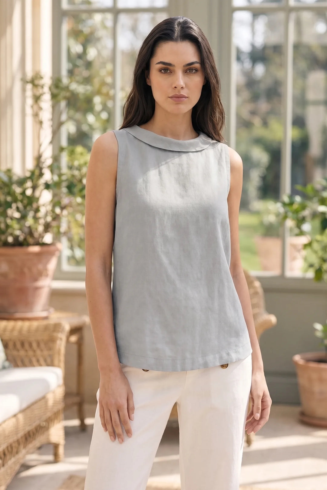 Model wearing grey sleeveless roll collar blouse in lifestyle setting