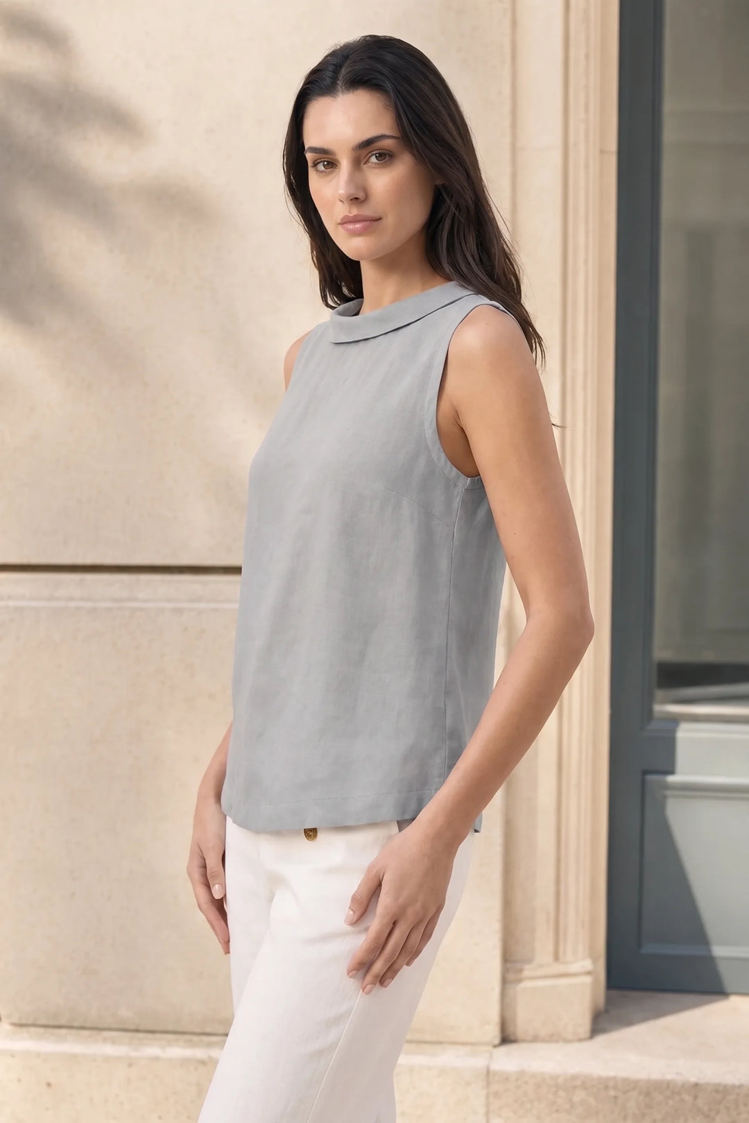 Grey sleeveless roll collar blouse on model in three-quarter turn