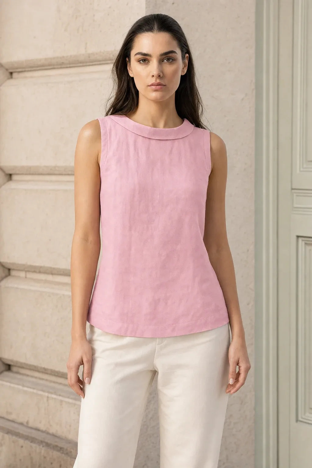 Pink sleeveless blouse with roll collar on model in contrapposto stance