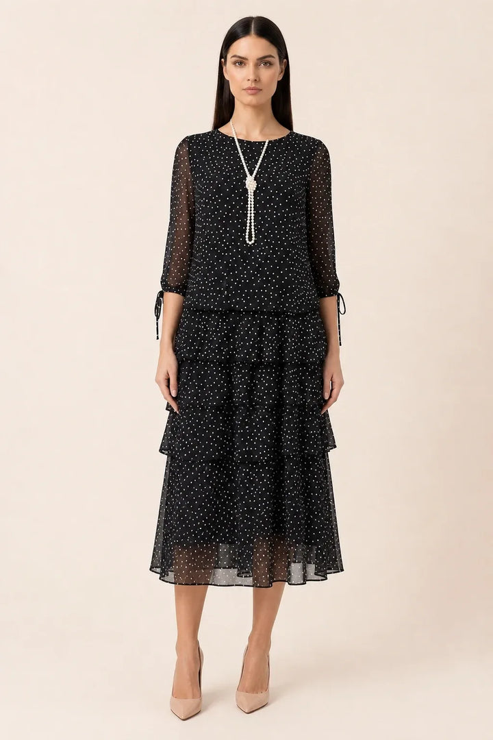 Black tiered polka dot midi dress on model in contrapposto stance