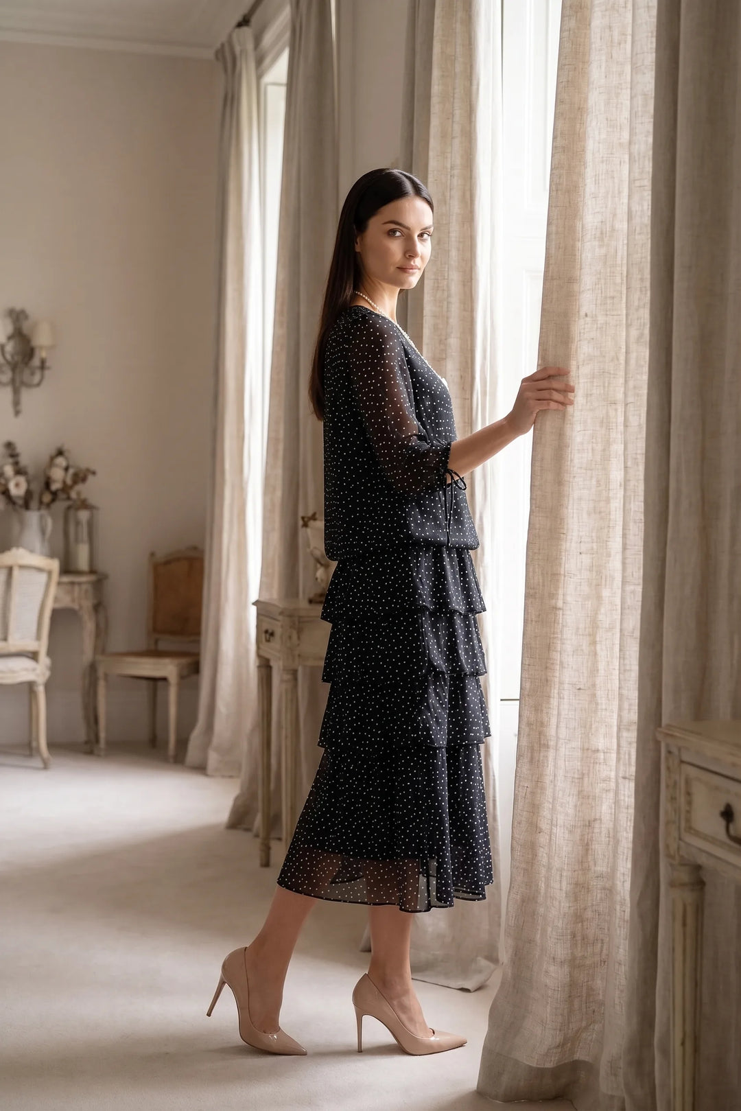 Model wearing black tiered polka dot midi dress in lifestyle setting