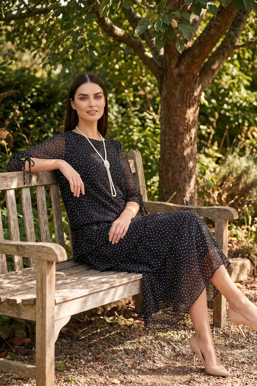 Model wearing black tiered polka dot midi dress in outdoor lifestyle setting