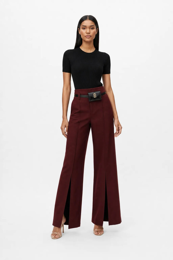 Wine red wide-leg trousers with belt worn by model in contrapposto stance