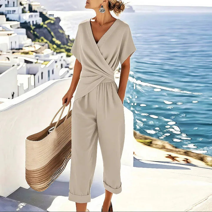 Woman wearing a sleeveless apricot twisted wrap jumpsuit, facing forward